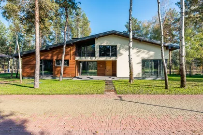 House with wood and white façade surrounded by tall pine trees