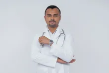 Doctor con estetoscopio y brazos cruzados sobre fondo liso