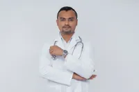 Doctor con estetoscopio y brazos cruzados sobre fondo liso