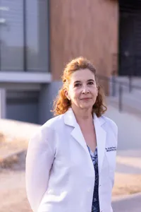Doctora con bata blanca frente a un edificio médico