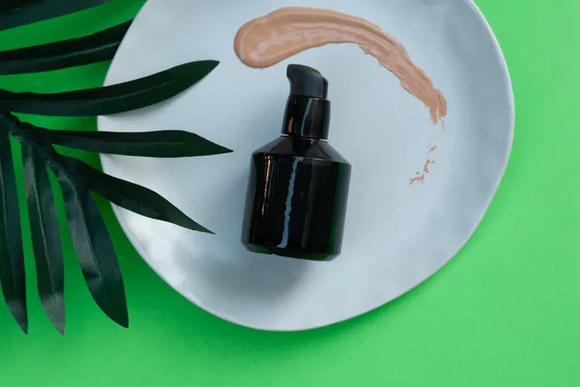 Black pump bottle on a white plate with green leaves