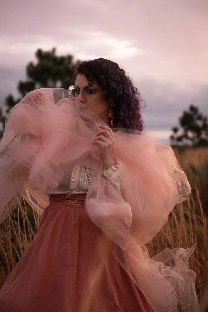 Fashion portrait of a woman in pink tulle in a field