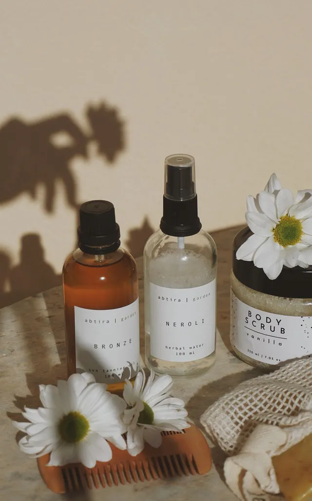 Three skincare bottles lined up with a flower behind them