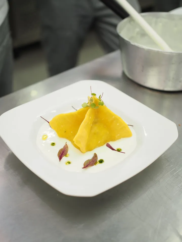 Ricotta ravioli plated with herbs on a white dish