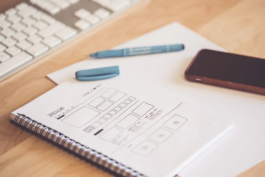 Wireframes sketched on a notebook next to a phone