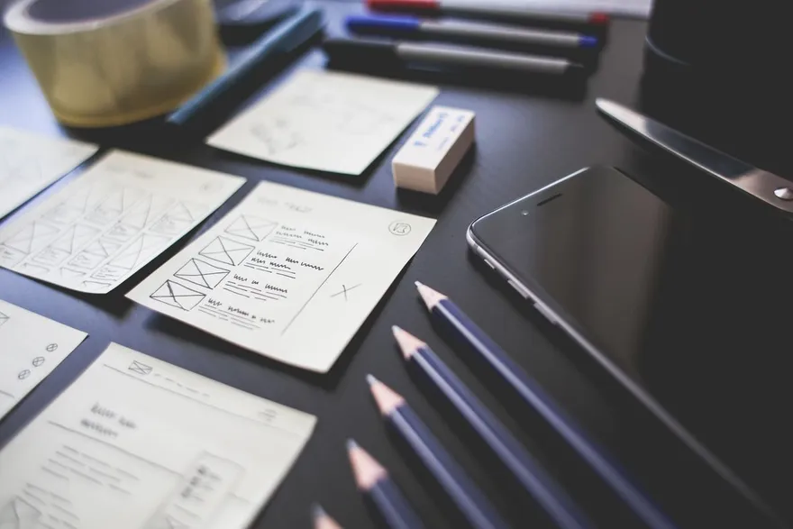 Interface plans and pencils laid out on a dark desk