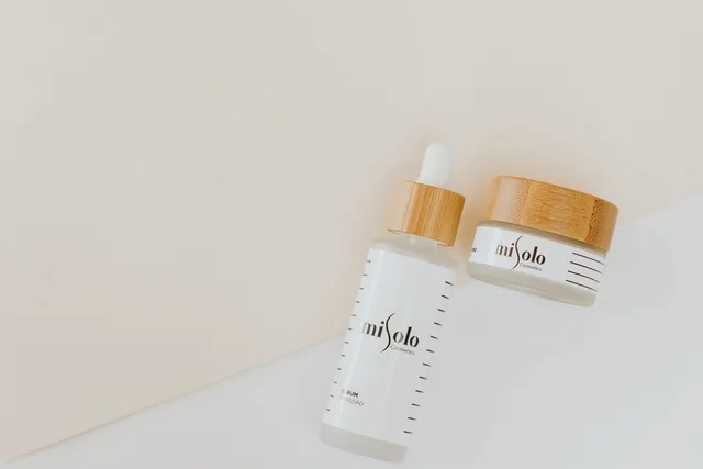 Dropper bottle and jar of skincare on a white surface