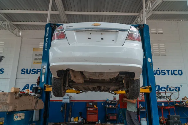 Underside of a white car on a lift during suspension work